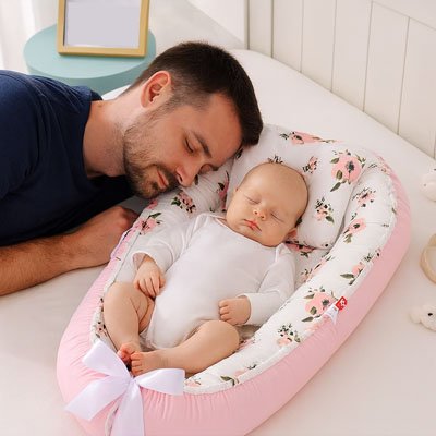 Reducteur de lit bébé en tissu doux installé dans un lit