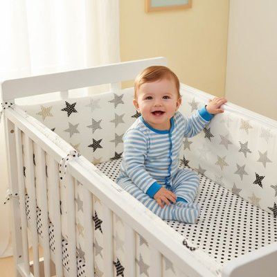 Tour de lit bébé en tissu placé dans un lit bébé